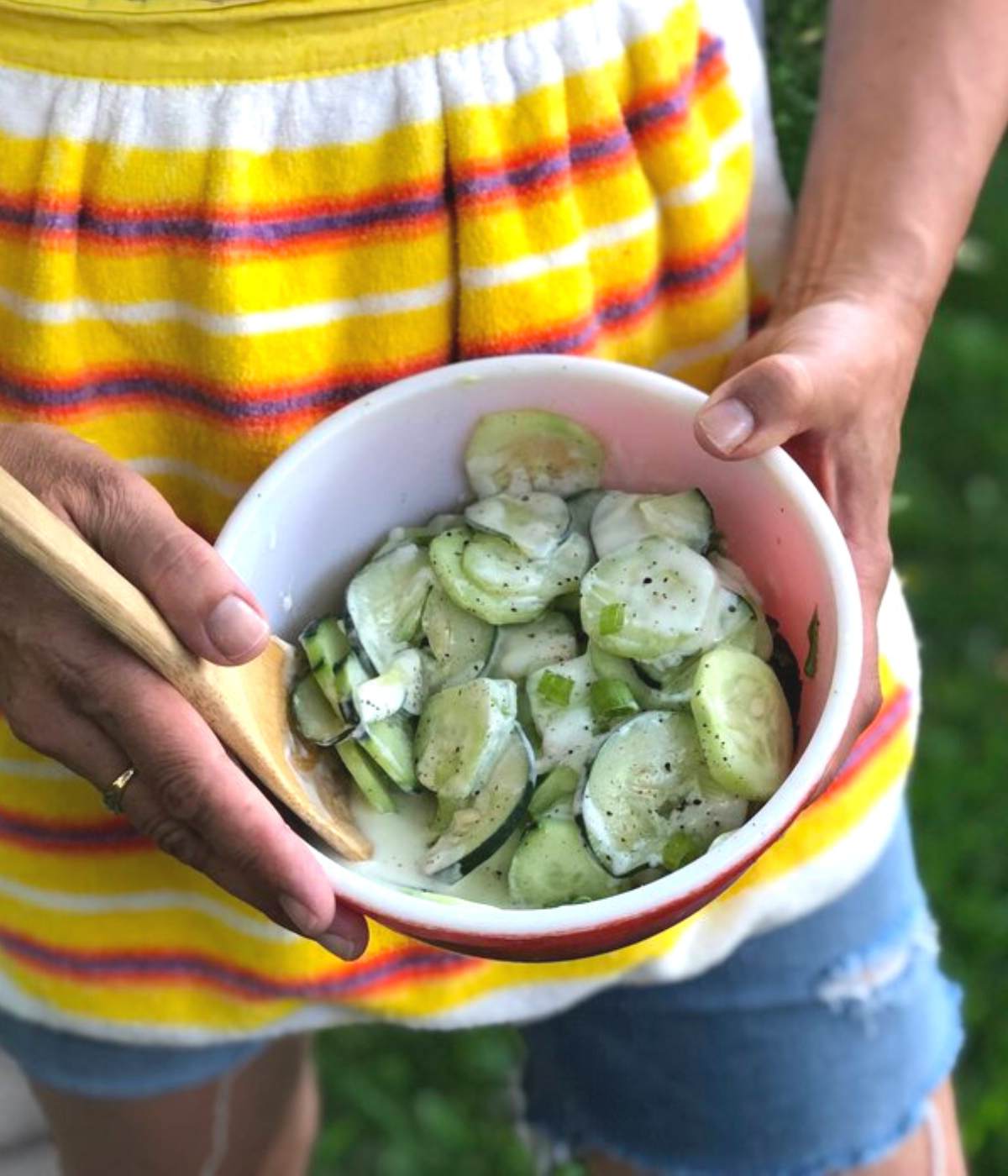 Hands holding a bowl of ede's creamy cucumbers