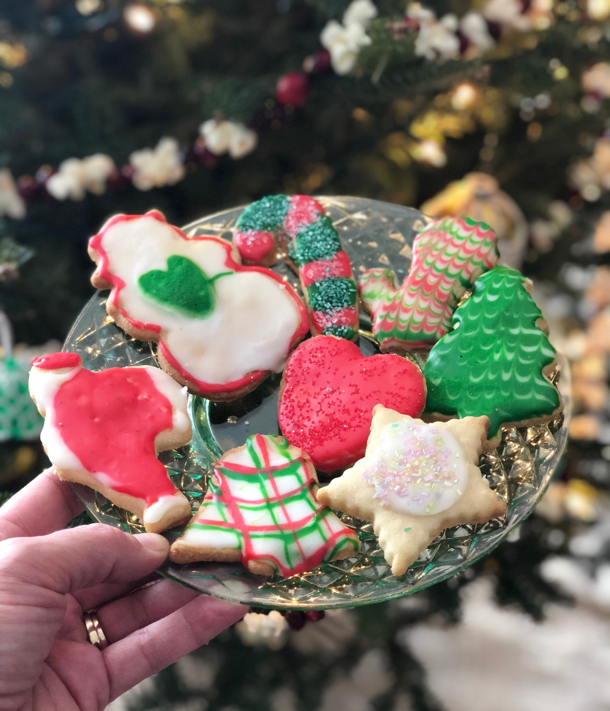 christmas themed, glazed, cut-out sugar cookies on a glass plate