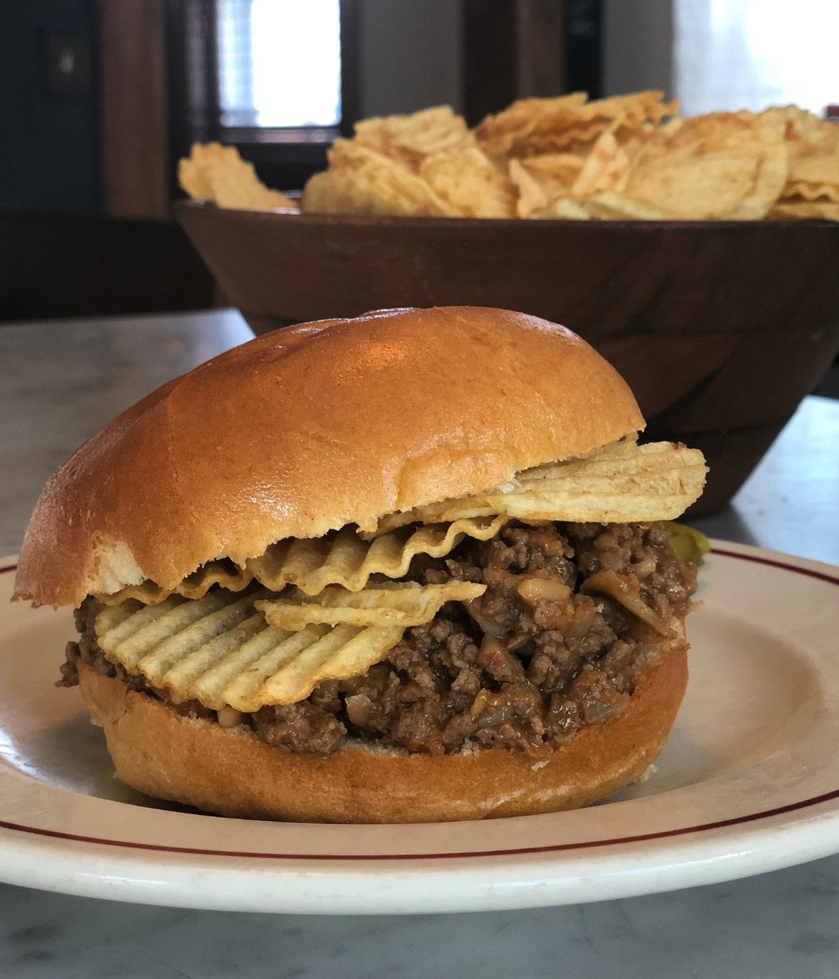 A sloppy joe on a plate with crispy potato chips